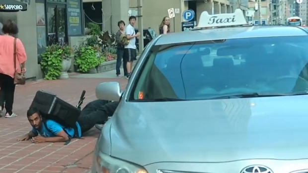 Toronto police are seeking four male witnesses after a video emerges that appears to show a taxi striking a cyclist and forcing him off the road. 